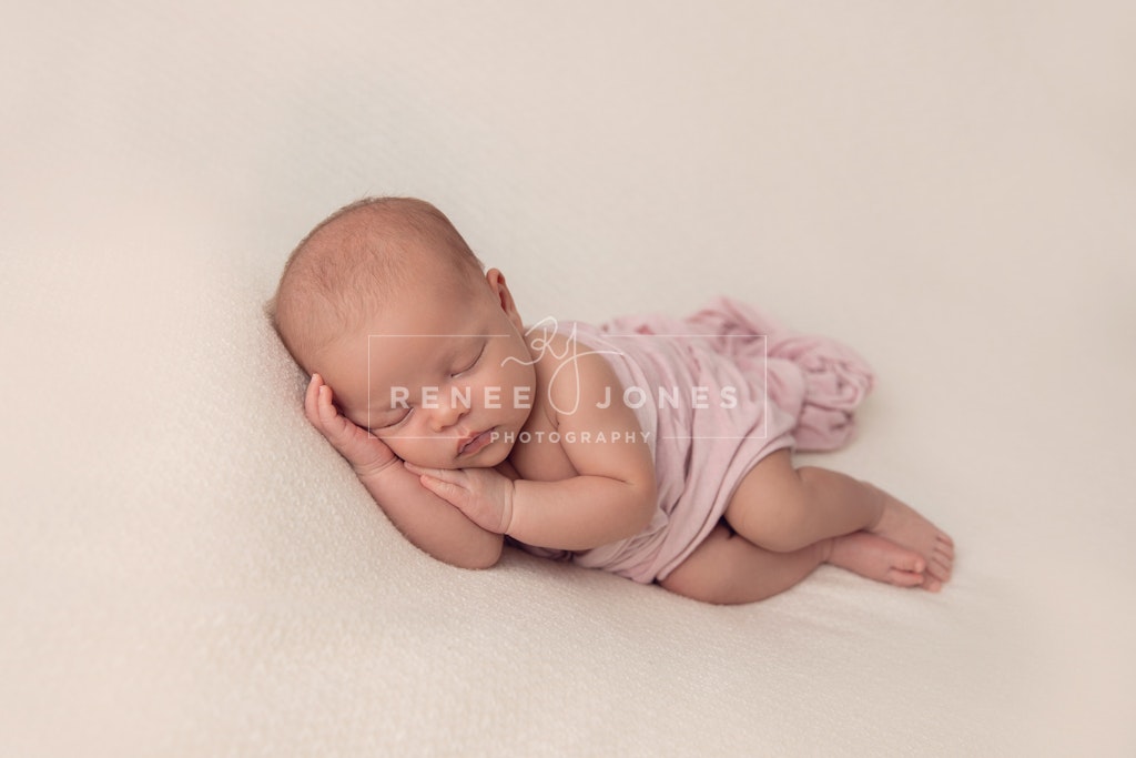 DAVIS_B-5 - Beautiful sleeping newborn in the side pose covered by a pale pink wrap on a cream blanket