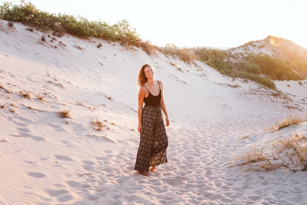21 - Girl with long blonde hair standing in white sand dunes smiling and looking happy.