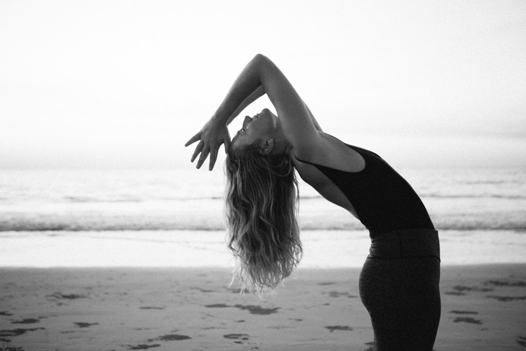 63 - Girl bending backwards into yoga pose over looking ocean.