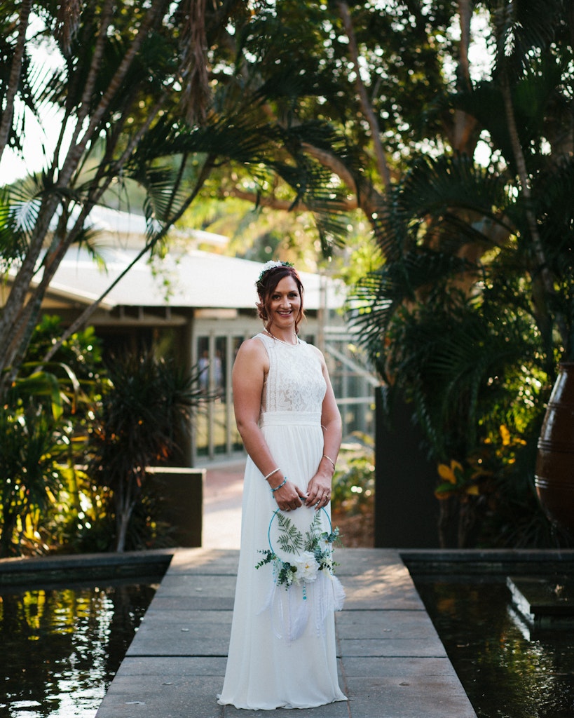 21 - Bride in her white wedding dress standing amongst green trees at Cable Beach resort in Broome.